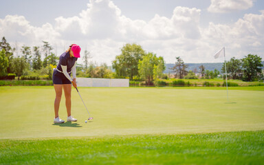 GOLF. Woman playing golf on a golf course in the sun