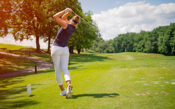 Sporty woman golfer player doing golf swing tee off on the green evening time, she presumably does exercise. Healthy Lifestyle Concept. Healthy Sport.