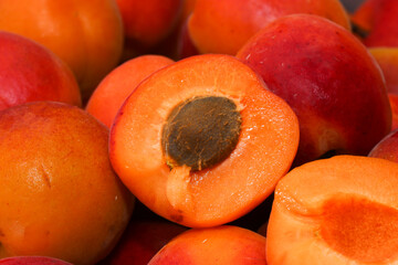 Lots of apricots. Fruit with a stone divided into 2 parts on the background of juicy apricots