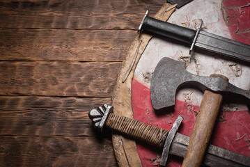 Old battle swords, axe and shield on the wooden table top view background with copy space.