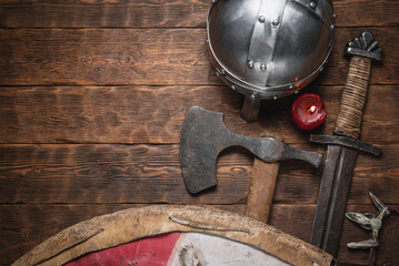 Old battle swords, axe and shield on the wooden table flat lay background with copy space.