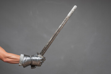 Sword in knight hand isolated on the gray background close up.