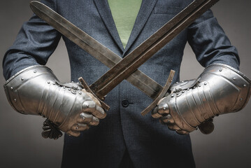 Businessman hands in the plate armor mittens with the two crossed swords close up. Help of a...