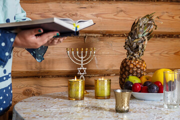 A Jewish woman prays the Siddur Kabalat Shabbat after lighting candles.