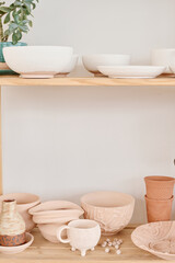 Display consisting of wooden shelves with creative handmade earthenware prepared for sale to clients of modern souvenir shop