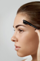 Beauty makeup. Eyebrows Care. Beautiful woman shaping brows with comb.  Correcting and contouring...