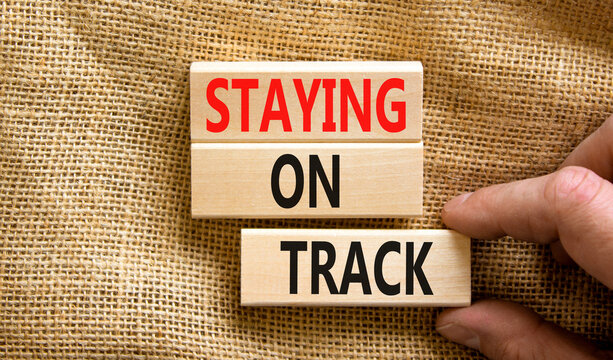 Staying on track symbol. Concept words Staying on track on wooden blocks on a beautiful canvas background. Businessman hand. Business, motivational and staying on track concept. Copy space.