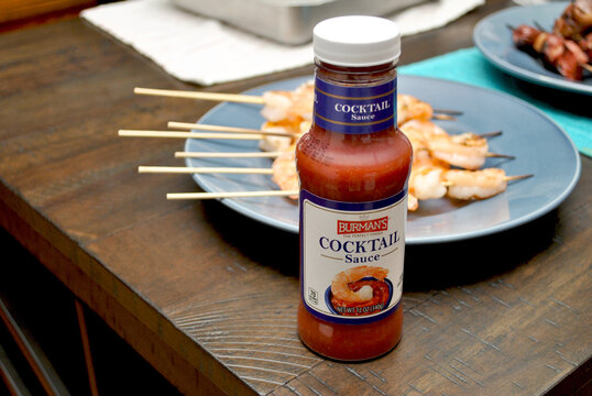 Burman's Brand Cocktail Sauce with a Plate og Grilled Shrimp on Skewers on the Bacground
