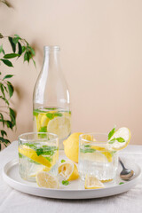 Refreshing summer drink with lemon and mint on the table. Lemonade in glasses and bottle