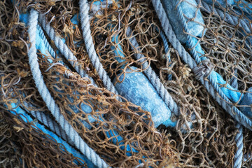 Buoys and a net tangible together as fishing gear or equipment at a harbor. Closeup of blue sea markers and mesh piled, grouped, or gathered together on a boat useful for a background.