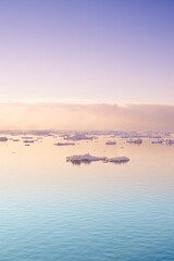 Seascape with floating glaciers at dawn. Serene winter arctic landscape. Icebergs on calm sea horizon at sunset in Denmark. Colorful nature scene of midnight sun. Polar summer in Ilulissat Greenland
