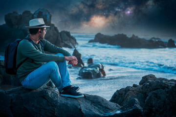 person sitting on the beach outdoors with a smartphone watching the horizon at night.