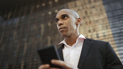 Fototapeta premium Adult american businessman wearing suit using cellphone on street