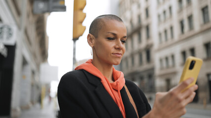 Adult white woman with short hairstyle using cellphone on street
