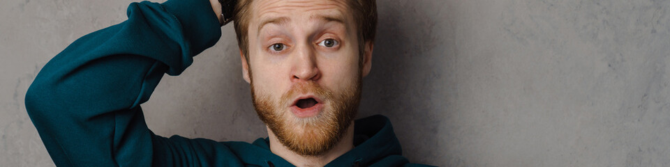 Fototapeta premium Bearded ginger man holding his head while expressing surprise