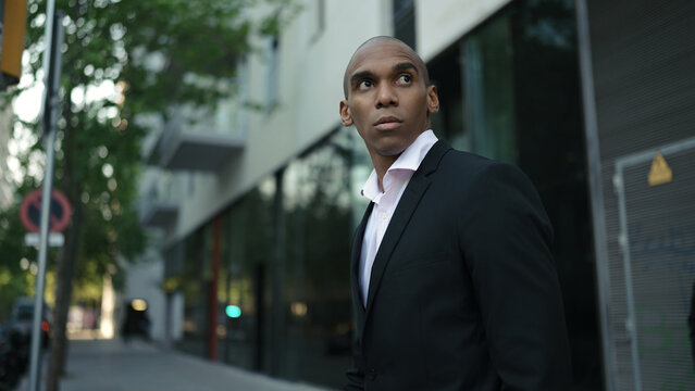 Adult african american businessman wearing suit walking along street