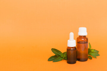 Natural Mint Essential Oil in a Glass Bottle. organic cosmetics with herbal extracts of mint on colored background