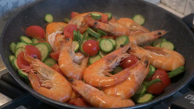Sauteed shrimp, courgettes, and cherry tomatoes, in a steaming pan