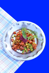 closeup the fried peas,cauliflower,red carrot, with mint and wild flower sous vegetable made in the steel plate with cloth over out of focus blue background.