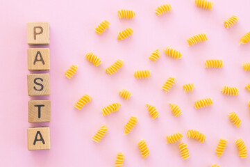 uncooked italian spiral pasta on pink background.
