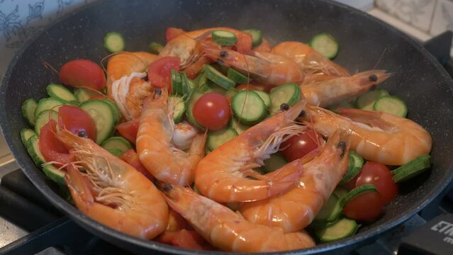 Sauteed shrimp, courgettes, and cherry tomatoes, in a steaming pan