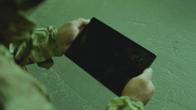 Air forces soldier , swat man or sapper aiming , holding and using black gadget and controlling military drone or futuristic robot machine during operation . Soldier looking to green screen . Close up