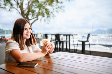Obraz premium Happy Asian woman smiling brightly in a modern coffee shop drinking coffee , The concept of drinking coffee