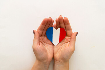Paper heart in the colors of the flag of France in female hands.