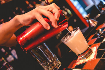 Closeup of young latin bartender making a delicious cocktail in the bar from a pub in the night