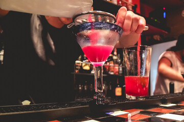 Closeup of young latin bartender making a delicious cocktail in the bar from a pub in the night