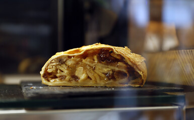 empanada dulce glaseada de hojaldre con manzana y crema partida por la mitad, viéndose su relleno