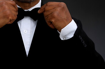 men adjusting his bow tie on grey background with people stock photo 