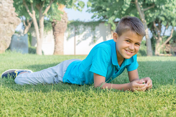 A teenager boy lies on the grass in the park.