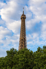 Obraz premium Partie supérieure de la Tour Eiffel devant un ciel partiellement nuagueux