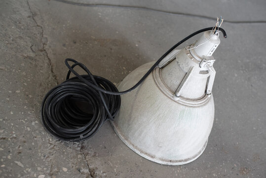 Old dirty industrial ceiling lamp and power cable on the dirty floor background.