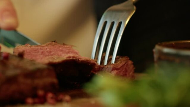 4K. Close-up of a juicy steak, which is cut with a fork and knife