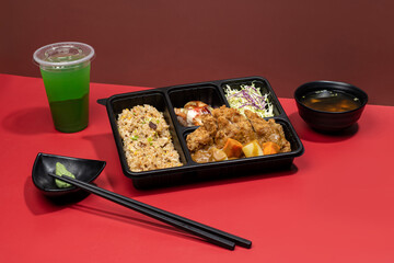 KATSU CURRY DON PREMIUM BENTO with mint margarita, sauce and chopsticks isolated on red background...
