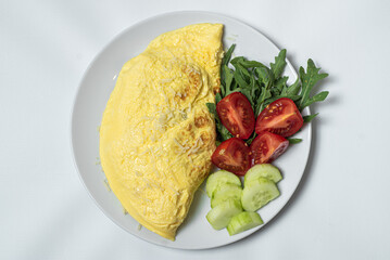 Vegetable egg omelette on a plate. Vegetarian omelet with fried red pepper, fresh parsley and spices. Fork, knife on a burlap and on white background. Breakfast recipe