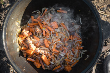 Cooking the meat in the kazan cauldron on the fire close up.