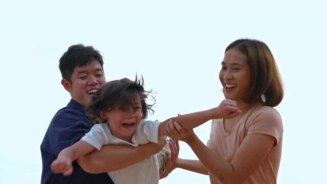 Happy family of dad and mom carrying son flying play outside on the beach together having fun enjoy freedom on summer vacation people lifestyle activity on weekend concept.