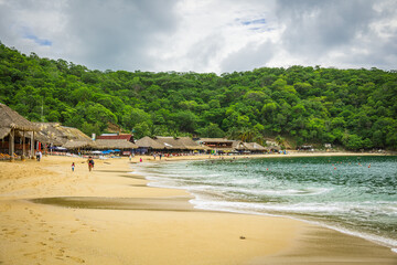 Fototapeta na wymiar Huatulco bays - Maguey beach. Beautiful beach with pristine waters, with turtles and fishes. Mexican beach with wooden huts by the sea