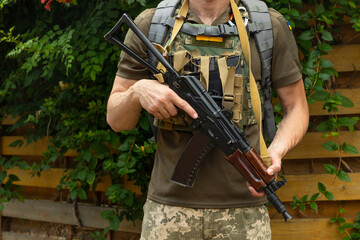 A military man in a military body armor with a tactical Kalashnikov automatic machine gun in his...