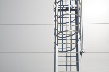a fire escape leading to the roof of a building made of metal structures and a pipe for connecting a fire hose.