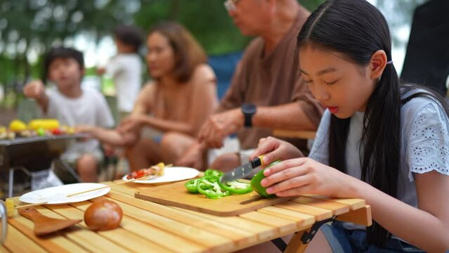 Girl preparing bell pepper of Happy family eating barbecue together, Cooking grilled bbq dinner outside beach, enjoy summer on the beach enjoy on weekend people lifestyle.