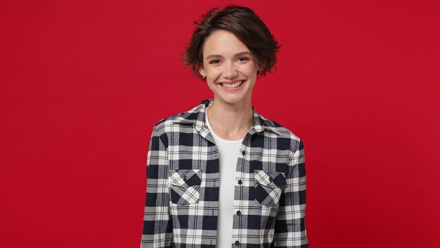 Smiling toothy charming happy young brunette woman 20s she wearing basic white t-shirt checkered shirt looking camera isolated against over plain solid dark red color wall background studio portrait