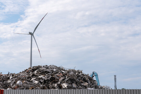 Windkraftanlage hinter Berg von Altmetall - Powered by Adobe