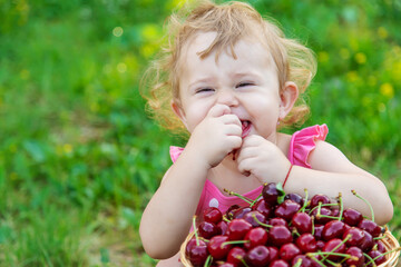 The child eats cherries in the garden. Selective focus.