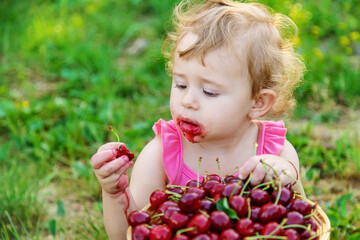 The child eats cherries in the garden. Selective focus.