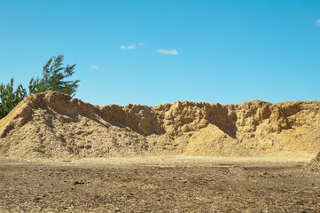 a product of wood processing, in the photo mountains of wood chips and sawdust against a blue sky