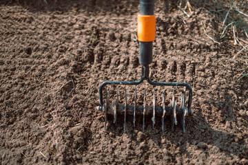 Loosening the soil with a rake in the greenhouse. Close up of an new metal garden rake cleaning...